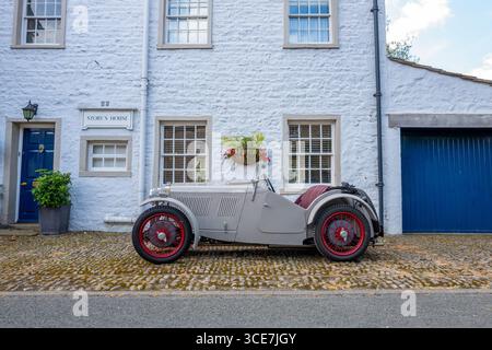 Vollständig restaurierte MG J2 Midget in Hellgrau gestrichen und auf einem Kopfsteinpflaster vor einem weiß gemalten Steinhaus stehend. Stockfoto