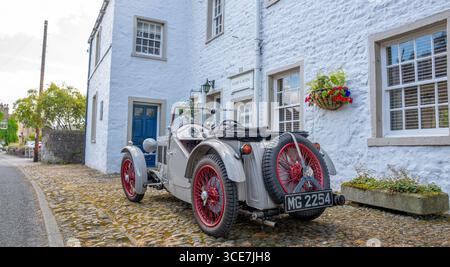 Vollständig restaurierte MG J2 Midget in Hellgrau gestrichen und auf einem Kopfsteinpflaster vor einem weiß gemalten Steinhaus stehend. Stockfoto