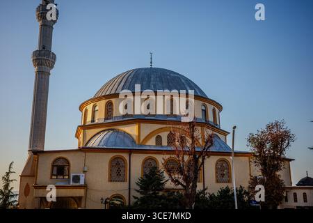 Elegante Moschee mit einer großen grauen Kuppel und einem hohen Minarett in warmen Abendlicht in Başiskele, Kocaeli, Türkiye, mit klassischem osmanischem Stil Stockfoto