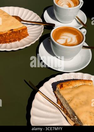 Nahaufnahme von zwei Tassen mit Kaffee und zwei Scheiben Kuchen auf grünem Couchtisch Stockfoto