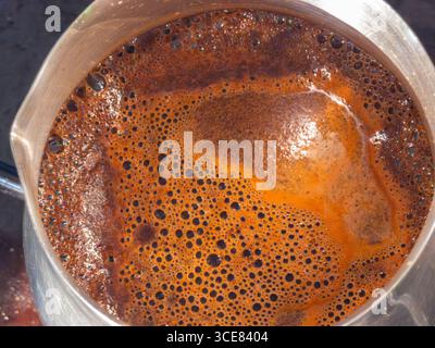 Das Brühen von heißem, aromatischem türkischem Kaffee in einem Cezve mit einer reichhaltigen Schaumschicht auf der Oberfläche unterstreicht die Kunst der traditionellen Zubereitung Stockfoto