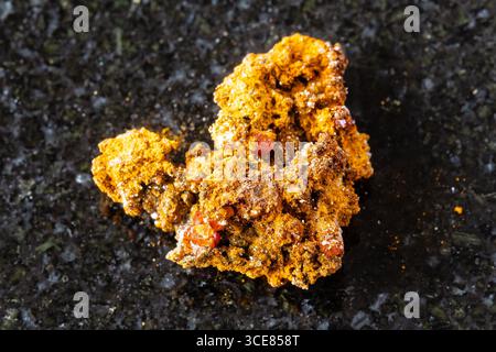 Probe von rohem Wulfenitgestein auf schwarzem Granithintergrund aus der Nähe von Xinjiang, China Stockfoto