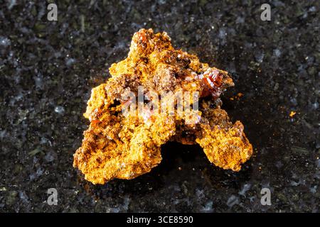 Probe von rohem Wulfeniterz auf schwarzem Granithintergrund aus der Nähe von Xinjiang, China Stockfoto