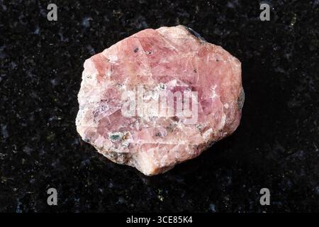 Probe von rosa Rubinmineralien auf schwarzem Granithintergrund aus nächster Nähe Stockfoto