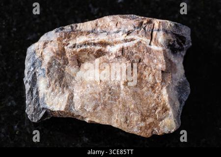 Probe von rohem Rhodonitmineral auf schwarzem Granithintergrund Nahaufnahme Stockfoto