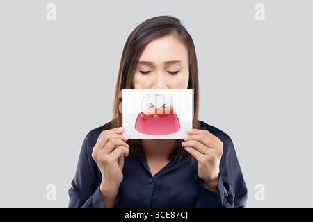 Eine Frau, die ein Papier mit blutender Zahnfleischillustration hält, die Mundgesundheit, Zahnhygiene und Zahnfleischkrankheitsprävention mit einem warmen Preisträger hervorhebt Stockfoto