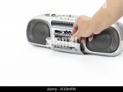 Eine Hand, die eine Kassette in einen tragbaren Vintage-Stereo-Player einführt, Retro-Audiogeräte, nostalgische Stimmung, isoliert auf weißem Hintergrund, Nahaufnahme Stockfoto