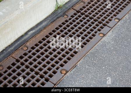 Gusseiserne Gully-Abflussabdeckung auf der städtischen Straße. Schutz vor Sturm und Regen Stockfoto