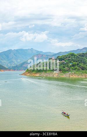 Eine malerische Szene im Salvajina Reservoir mit üppigen Hügeln, ruhigen Gewässern und kleinen Booten, die die Schönheit der Natur in Popayán, Kolumbien, zeigen. Stockfoto
