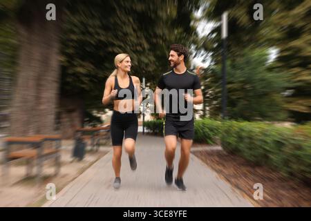 Mann und Frau in Sportbekleidung, die draußen laufen, Motion Blue-Effekt Stockfoto