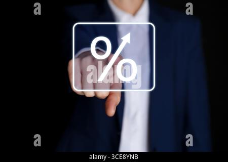 Geschäftsmann, der das Prozentzeichen auf dem virtuellen Bildschirm vor schwarzem Hintergrund berührt, Nahaufnahme Stockfoto
