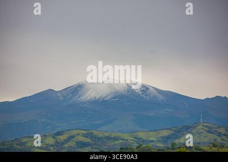 Ein atemberaubender Blick auf den schneebedeckten Vulkan Puracé, umgeben von grünen Hügeln in Popayán, Cauca, Kolumbien. Die majestätische Schönheit der Natur. Stockfoto