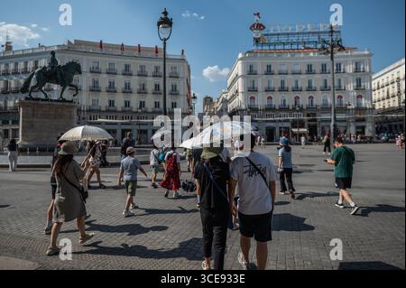 Madrid, Spanien. August 2025. Touristen mit Sonnenschirmen besuchen Puerta del Sol an einem heißen Sommertag. Spanien steht in vielen Teilen der spanischen Halbinsel vor einer Hitzewelle mit extrem hohen Temperaturen von mehr als 40 Grad Celsius. Quelle: Marcos del Mazo/Alamy Live News Stockfoto