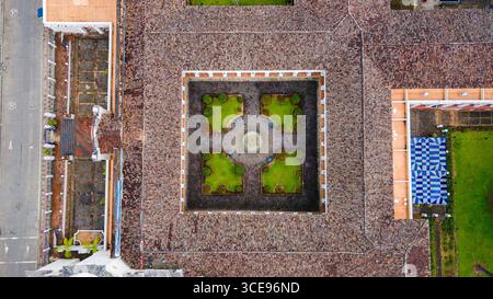 Atemberaubender Blick aus der Luft auf einen symmetrischen Innenhof mit grünen Gärten und traditionellen Dächern in Popayán, Cauca, Kolumbien. Stockfoto