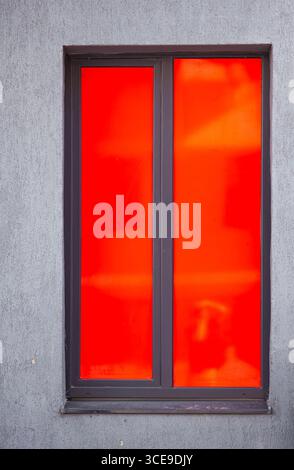 Rotes geschlossenes Fenster an einer grauen Wand. Stockfoto