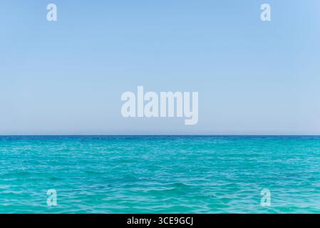 Ruhiges türkisfarbenes Meer trifft auf klaren blauen Himmel am Horizont, ideal für Reisen, Sommer und Entspannung Stockfoto