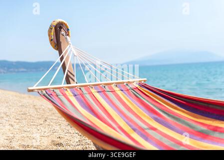 Gestreifte Hängematte am Kiesstrand am ruhigen Meer, perfekt für Sommererholung und Badeurlaub Stockfoto