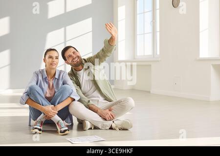 In einem geräumigen Zimmer sitzt das Paar bequem auf dem Boden und spricht über das Layout ihres neuen Heims. Stockfoto