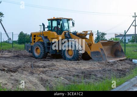 Gelber Bagger, der den Boden auf der Baustelle nivelliert. Bulldozer arbeitet im Steinbruch. Planierraupe kämmt den Boden am Abend. Steinbruch Ex Stockfoto
