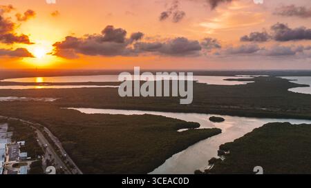 Ein wunderschöner Sonnenuntergang über einem großen Gewässer. Der Himmel ist voller Wolken, und die Sonne geht in der Ferne unter. Das Wasser ist ruhig. Luftaufnahmen Stockfoto