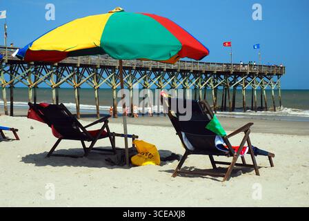 In Myrtle Beach, South Carolina, verbringen die Menschen ihre Sommerferien in einem Liegestuhl unter einem Sonnenschirm Stockfoto