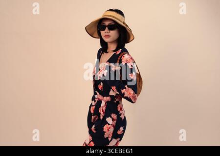 Stilvolle Frau im Blumenkleid mit Hut und Sonnenbrille Stockfoto