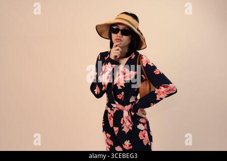 Stilvolle Frau im Blumenkleid mit Hut und Sonnenbrille Stockfoto