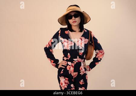 Stilvolle Frau im Blumenkleid mit Hut und Sonnenbrille Stockfoto