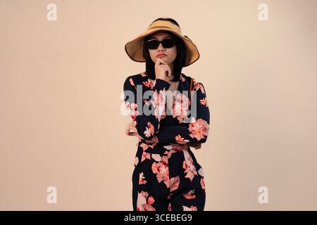 Stilvolle Frau im Blumenkleid mit Hut und Sonnenbrille Stockfoto