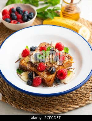 Französischer Toast mit Butter und roten Früchten und Banane. Stockfoto