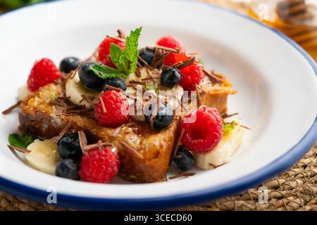 Französischer Toast mit Butter und roten Früchten und Banane. Stockfoto