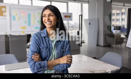 Glückliche indische Startup-Besitzerin, die am Arbeitsplatz steht Stockfoto