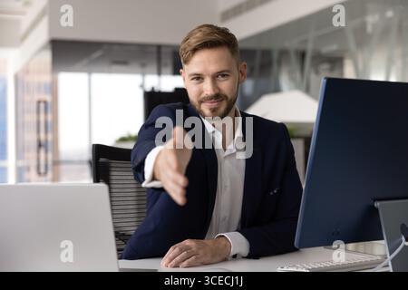 Positiver junger Geschäftsleiter, der sich für das Zittern ausgibt Stockfoto