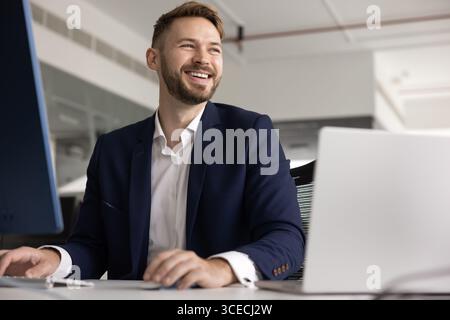 Positiv aussehender junger kaukasischer Berufsmann, der am Laptop arbeitet Stockfoto