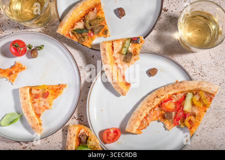 Frische vegetarische Pizzascheiben mit Zucchini, Auberginen, Paprika, Oliven und Tomaten, serviert auf einem rustikalen Tisch. Eine köstliche pflanzliche Mahlzeit ID Stockfoto
