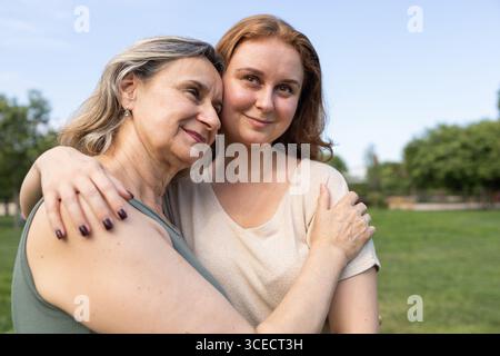 Eine ruhige Outdoor-Szene, die einen berührenden Moment zwischen Mutter und Tochter zeigt und deren enge Verbundenheit und Verbindung unterstreicht. Ihre Ausdrücke beziehen sich auf Stockfoto