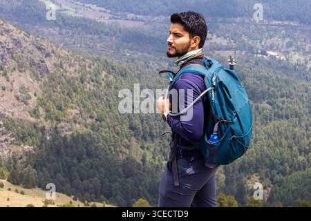 Ein Wanderer steht auf einem Bergrücken und blickt nachdenklich auf das malerische Tal darunter. Er trägt Outdoor-Ausrüstung und einen großen Rucksack und verkörpert den Advent Stockfoto