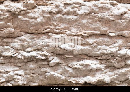 Nahaufnahme der Natursteinstruktur mit mehrschichtigen Mustern. Die raue Oberfläche und die hellbraunen Farbtöne erzeugen einen organischen und haptischen visuellen Effekt, hig Stockfoto