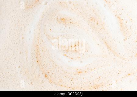 Nahaufnahme einer Kaffeeschaum-Oberfläche mit glatten Blasen und hellbraunen Wirbeln. Die Makroaufnahme hebt die komplizierte Textur der Creme hervor Stockfoto