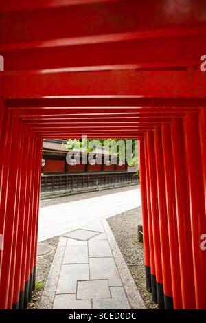 Majestätischer Blick durch die lebendige rote Torii-Passage am Kitano Tenmangu-Schrein in Kyoto, Japan, mit traditioneller japanischer Architektur und Kultur Stockfoto