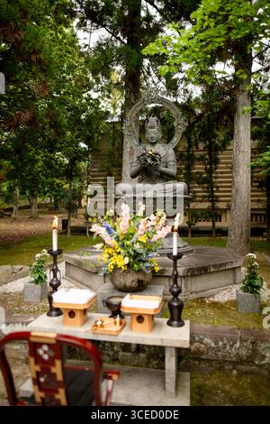 Eine friedliche Buddha-Statue umgeben von üppigem Grün und Blumen im Ninna-JI-Tempel in Kyoto, Japan, fängt das Wesen der Ruhe und des spirituellen ein Stockfoto