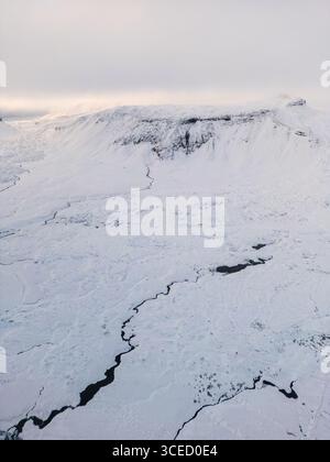 Aus der Vogelperspektive auf Islands dramatische Winterlandschaft mit weiten, schneebedeckten Flächen und zerklüftetem Gelände. Die ruhige, unberührte Wildnis Stockfoto