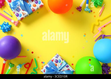 Farbenfroher Partyrahmen Hintergrund mit Ballons und Geschenken auf gelbem Hintergrund Stockfoto