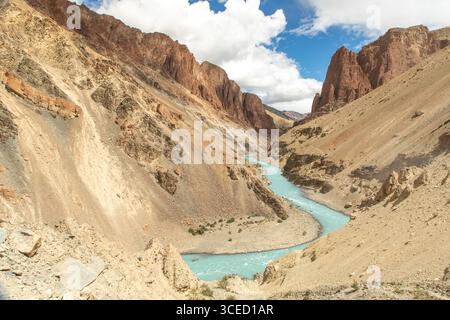 Eine atemberaubende Landschaft eines türkisfarbenen Flusses, der sich durch zerklüftete Berge in Ladakh schlängelt. Das trockene Gelände und der helle Himmel unterstreichen die natürliche Schönheit von Th Stockfoto