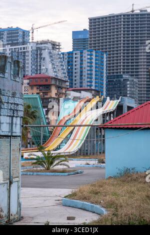 In Batumi, Georgia, befinden sich pulsierende Wasserrutschen inmitten städtischer Hochhäuser. Die lebhaften Farben stehen im Kontrast zum Stadtbild und betonen die Freizeit am Morgen Stockfoto