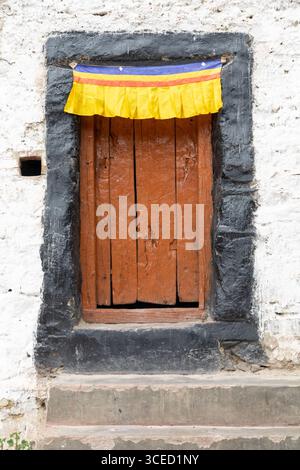 Eine rustikale Holztür mit einem leuchtenden gelben, roten und blauen Stoff im Zanskar-Tal, Ladakh, Indien, mit einem traditionellen Himalaya-Archit Stockfoto
