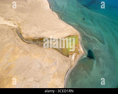 Aus der Vogelperspektive auf den faszinierenden Pangong TSO Lake in Ladakh, Indien, mit dem pulsierenden türkisfarbenen Wasser, das auf das karge sandige Gelände trifft, was eine Stockfoto