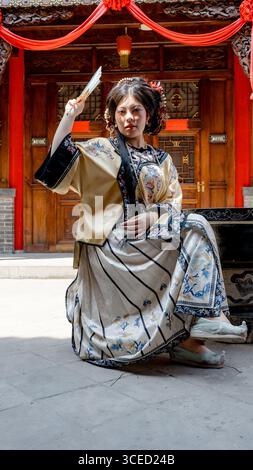 Frau in traditioneller Kleidung der Qing-Dynastie, mit einem Ventilator und Blick in die Kamera. Fotografiert in Pingyao, China, mit reicher Kultur Stockfoto