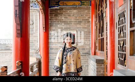 Eine Frau in traditioneller Kleidung der Qing-Dynastie steht in Pingyao, China, und blickt auf die Kamera. Die historische Kulisse unterstreicht Chinas reiche CUL Stockfoto