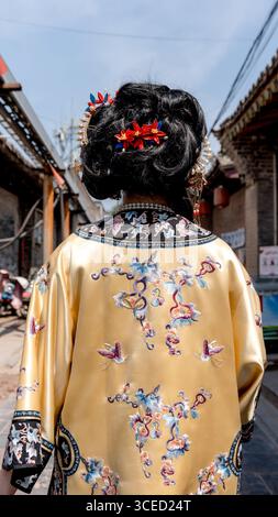 Rückansicht einer nicht erkennbaren Frau in traditioneller Kleidung der Qing-Dynastie, verziert mit exquisiter Stickerei, mit Blick auf die Kamera in Pingyao, Chi Stockfoto